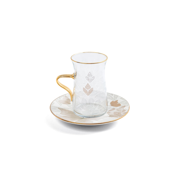 Ceramic cup with gold accents and a matching saucer on a white background