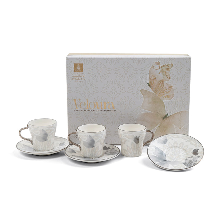 Set of ceramic tea cups and saucers with a decorative box in the background