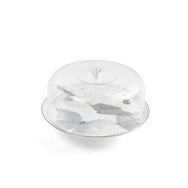 Clear cake stand with marble base and silver cake server on a white background