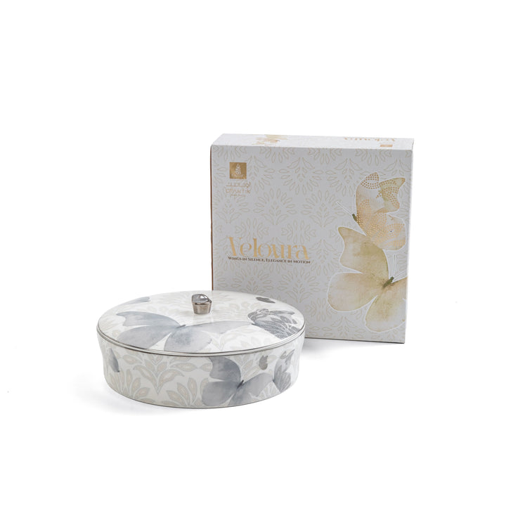 Decorative ceramic container with floral design next to a branded box on a white background