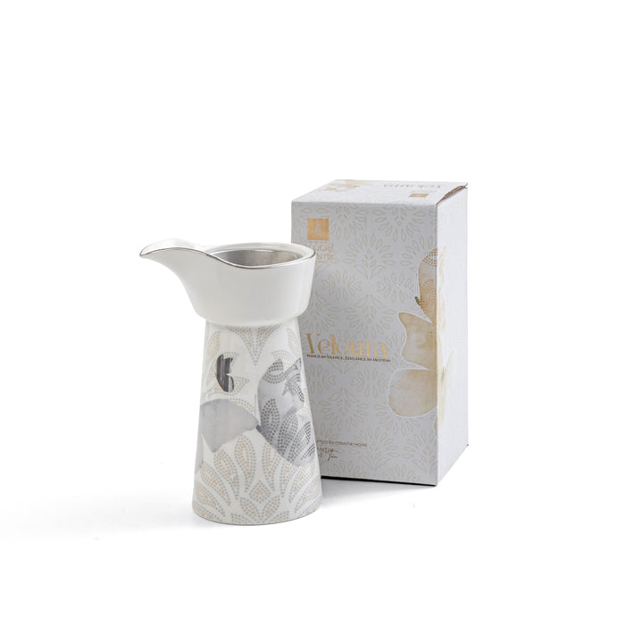 Ceramic pitcher with floral design next to its packaging on a white background