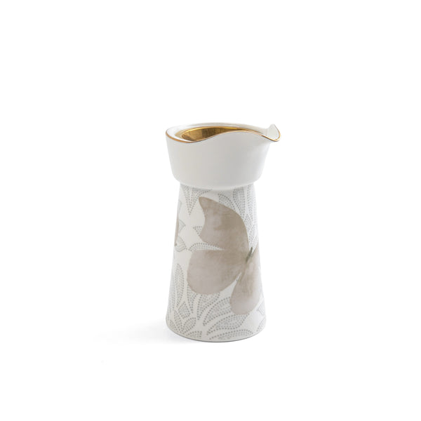 White ceramic pitcher with gold rim and leaf design on a white background
