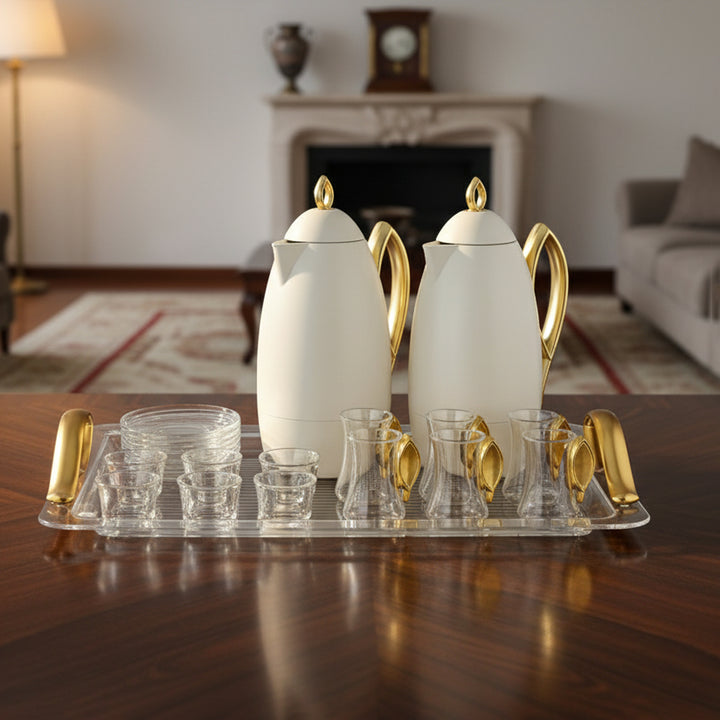 Set of white teapots with gold handles on a wooden table in a living room.