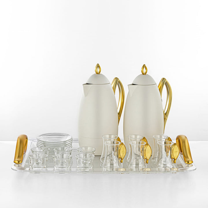 White and gold tea set with glass cups on a white background