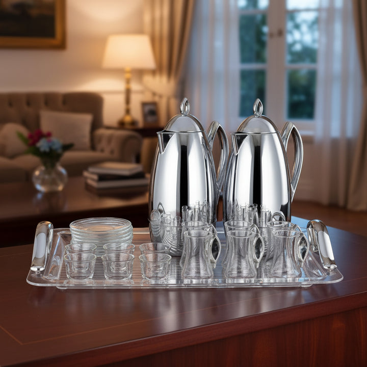 Silver tea set with teapots, cups, and a tray on a wooden table in a living room.
