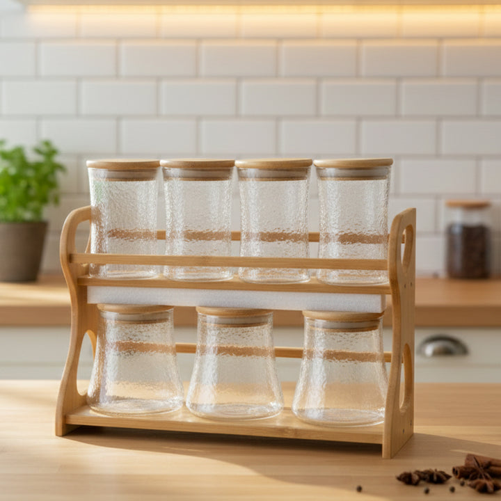 Clear glass jars with wooden lids on a wooden rack in a kitchen setting.