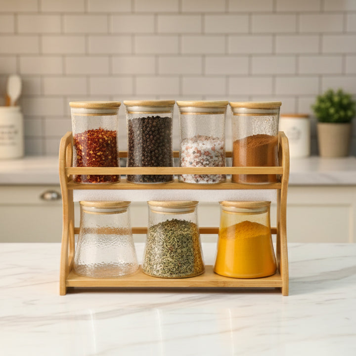 Spice rack with glass jars containing various spices on a kitchen counter.