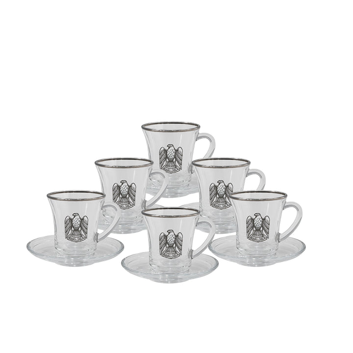 Set of six glass cups with saucers featuring an eagle emblem on a white background