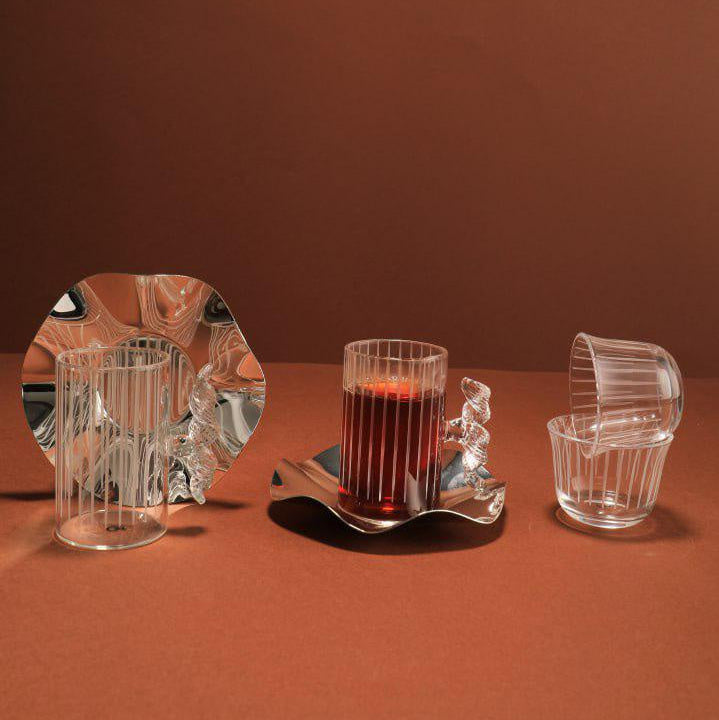 Set of glassware including a mug, small glass, and bowl on a brown surface with a brown background