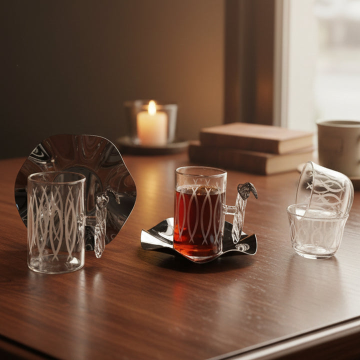 Two glass mugs with a dark liquid on a wooden surface, one mug is on a decorative tray.
