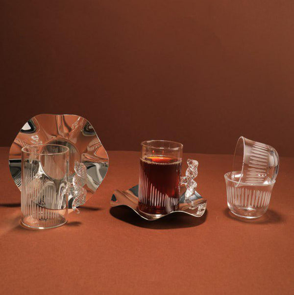 Set of glassware including a mirror, a glass with a dark liquid, and a small glass on a brown background
