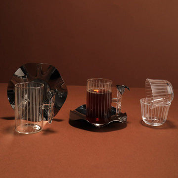Set of glassware including a candle holder with a lit candle on a brown background