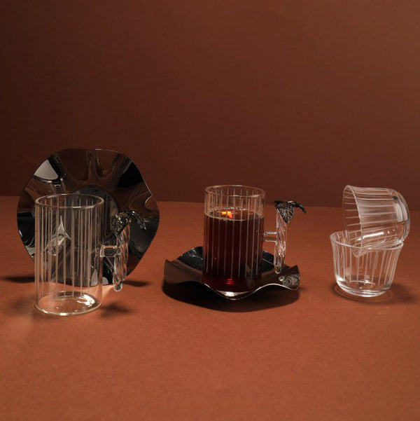 Set of glassware including a candle holder with a lit candle on a brown background