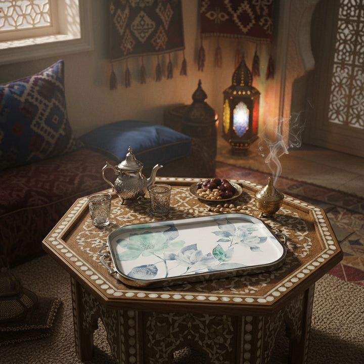 Decorative table setting with teapot, glasses, and tray in a cozy room with lanterns and cushions.