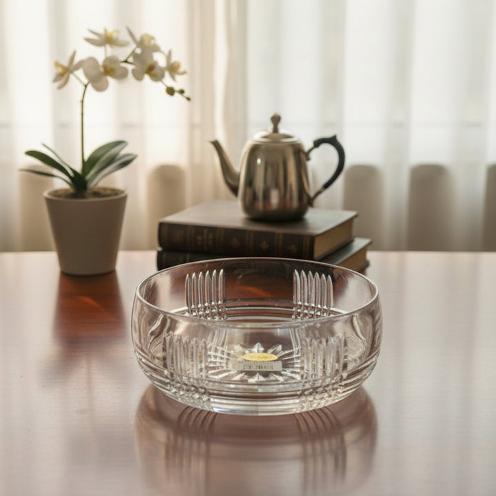 Clear glass bowl on a table with a teapot and books in the background