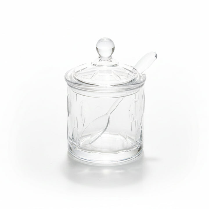 Clear glass jar with a lid and spoon on a white background