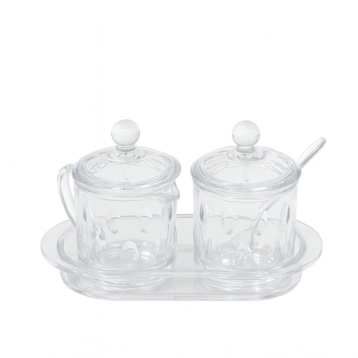 Clear glass condiment set with two jars and a tray on a white background