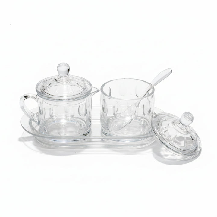 Clear glass tea set with cups, saucers, and a tray on a white background