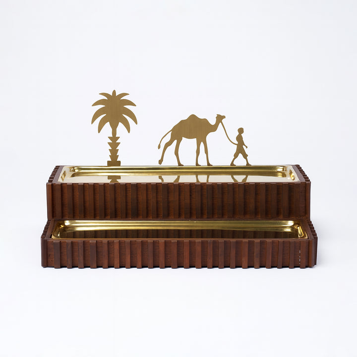 Decorative metal sculpture with camel, palm tree, and person on a white background