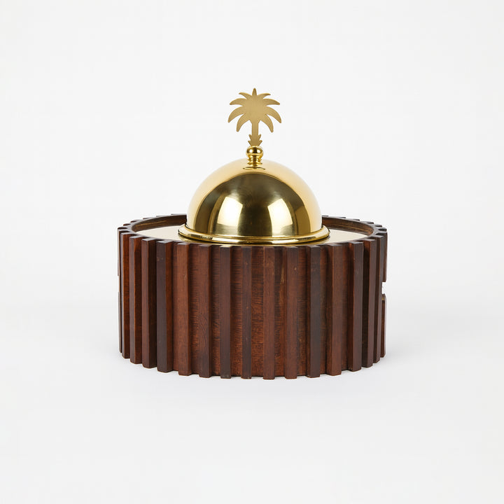 Decorative object with a gold dome and palm tree on a wooden base against a white background