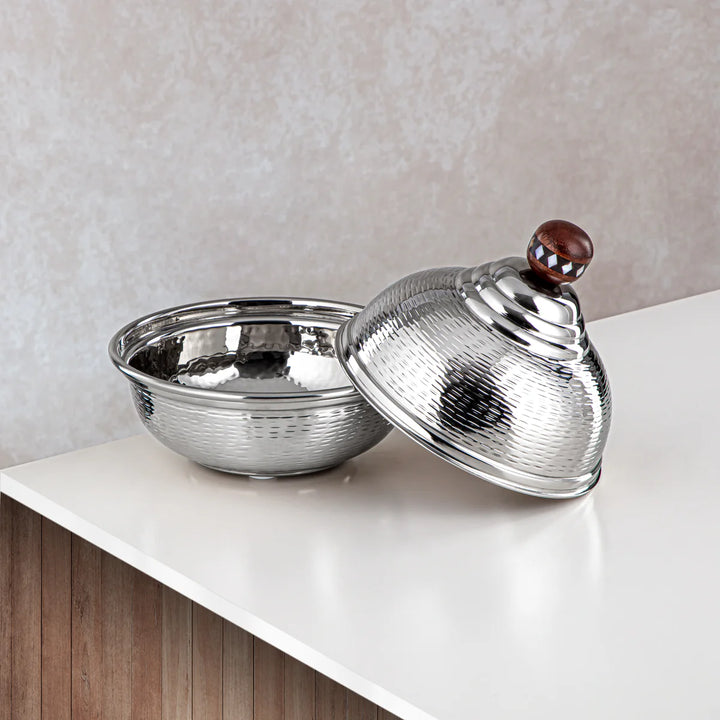 Silver bowl with textured lid on a white surface