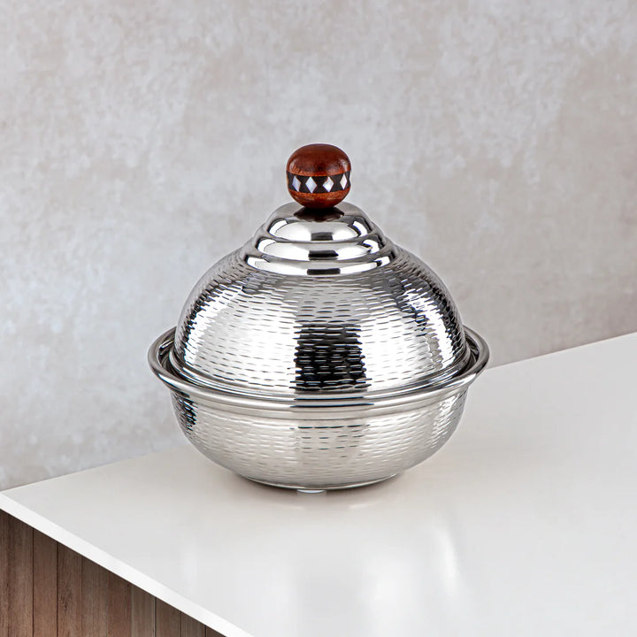 Silver textured bowl with a wooden knob on a white surface