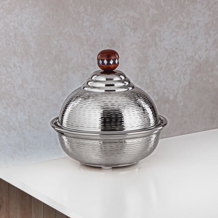 Silver textured container with a decorative lid on a light surface.
