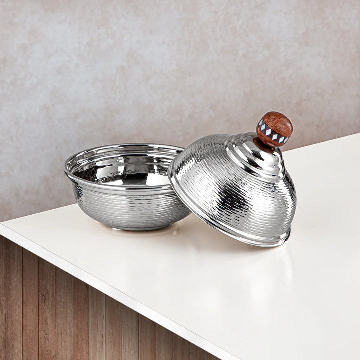 Silver bowl with textured lid on a white surface