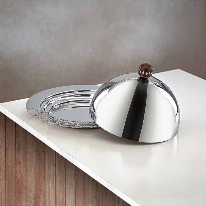 Silver serving dish with a decorative handle on a white surface