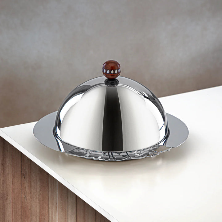 Silver dome-shaped container with a red and white checkered knob on a neutral background