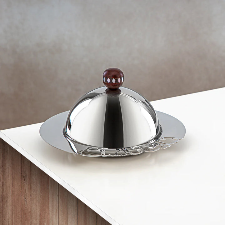 Silver butter dish with a brown knob on a white surface