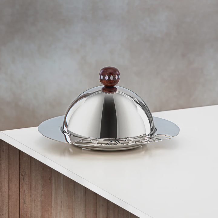 Silver dome-shaped object with a brown knob on a white surface