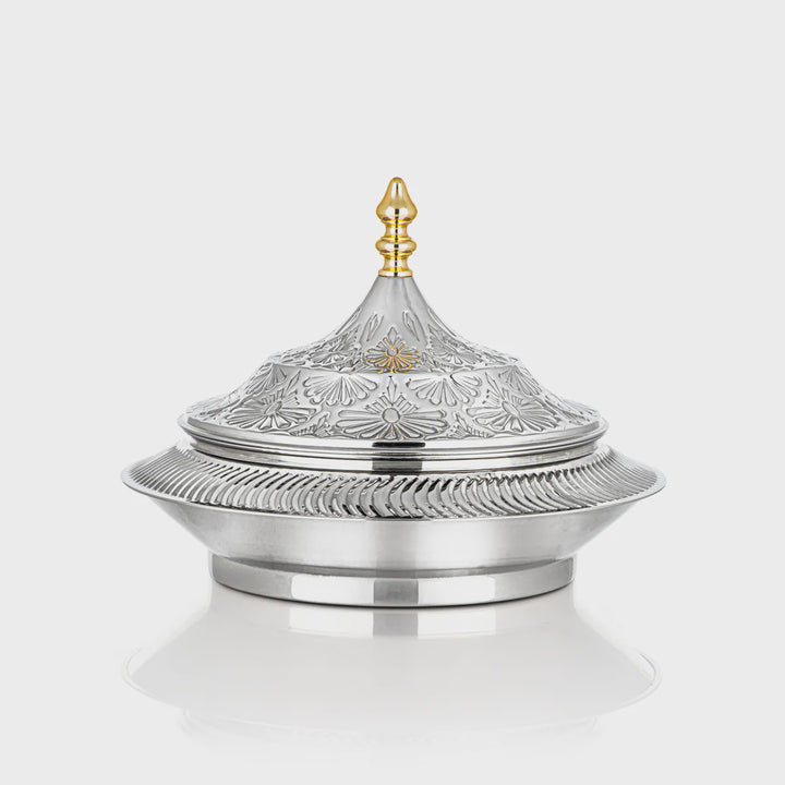 Decorative silver container with intricate designs on a white background