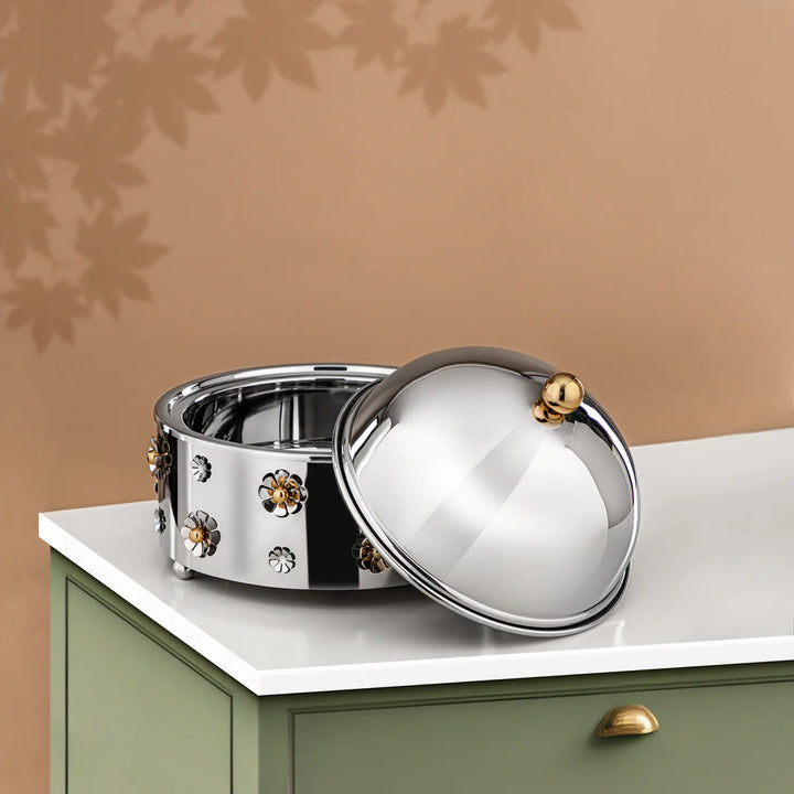 Decorative metal bowl with a lid on a white surface against a beige wall.