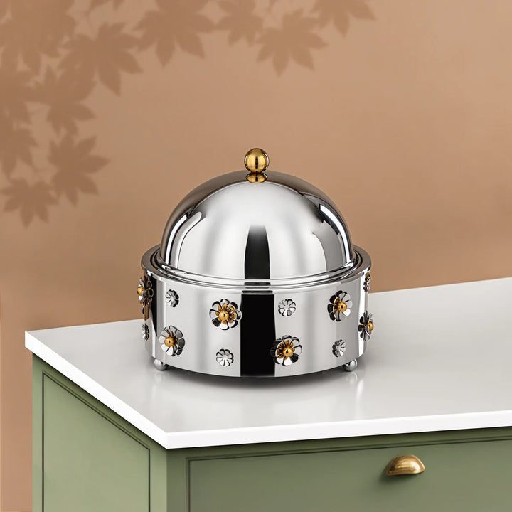 Decorative silver dome with floral embellishments on a white surface against a beige wall.
