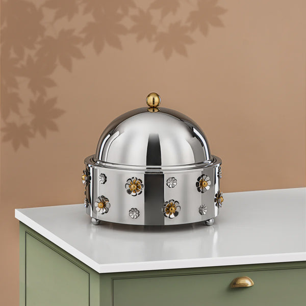 Decorative metal dome with floral designs on a white surface against a beige wall.