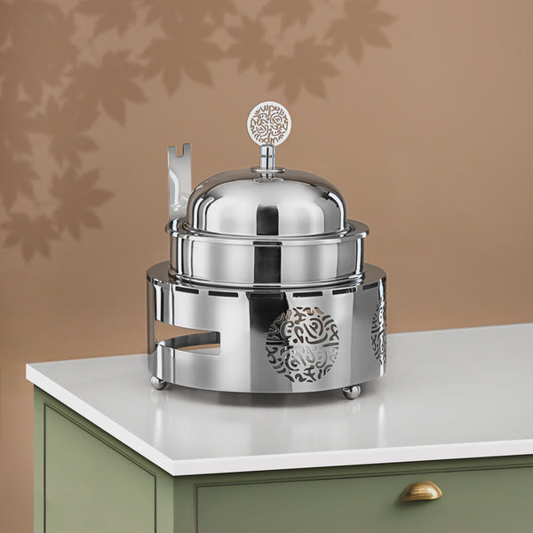 Silver chafing dish on a white surface with a brown background