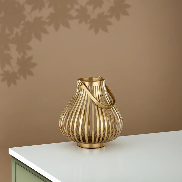 Gold decorative vase on a white surface with a brown wall background