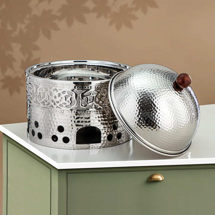 Decorative metal container with a textured lid on a light surface.