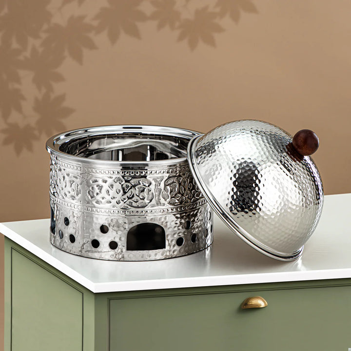 Decorative metal container with a wooden handle on a beige surface