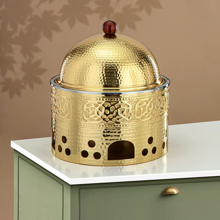 Decorative gold metal container with intricate patterns on a white surface.