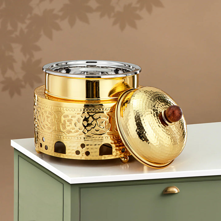 Gold decorative container with intricate designs on a white surface against a beige background