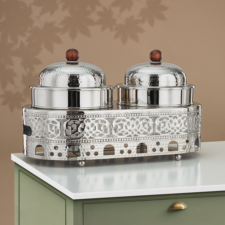 Decorative silver serving set with two covered dishes on a white surface.