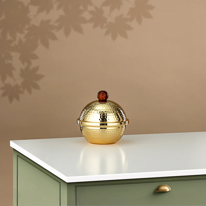 Gold decorative object on a white surface with a beige wall in the background