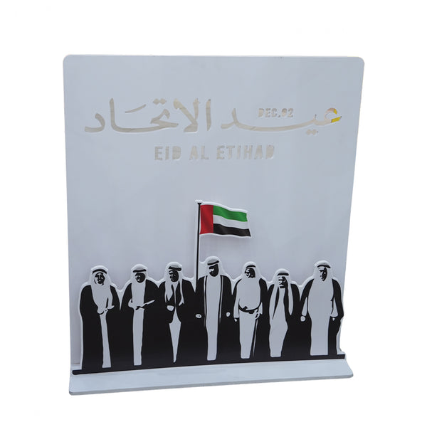 Decorative plaque with silhouettes of people and a flag, featuring 'Eid Al Etihad' text.