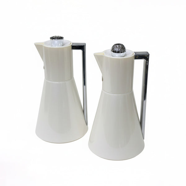 Two white ceramic pitchers with black nozzles on a white background