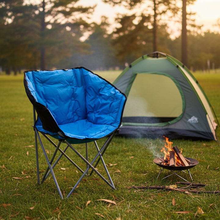 Blue camping chair in front of a green tent with a campfire in the foreground