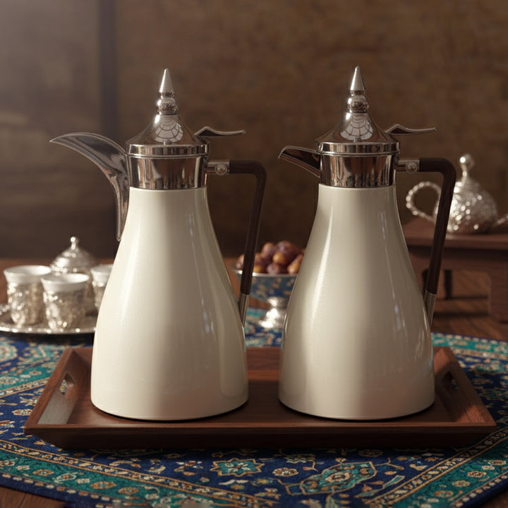 Two white ceramic teapots with silver lids on a wooden tray.