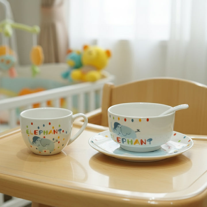Children's ceramic cup and saucer set with elephant design on a tray in a nursery.