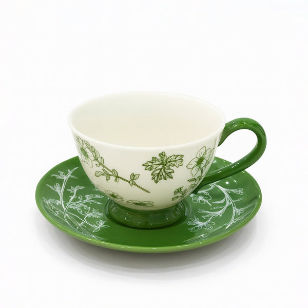 Teacup and saucer with green floral patterns on a white background